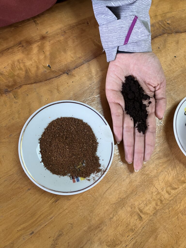 Premium coffee grounds in a plate and low grade coffee grounds being shown in someone's palm