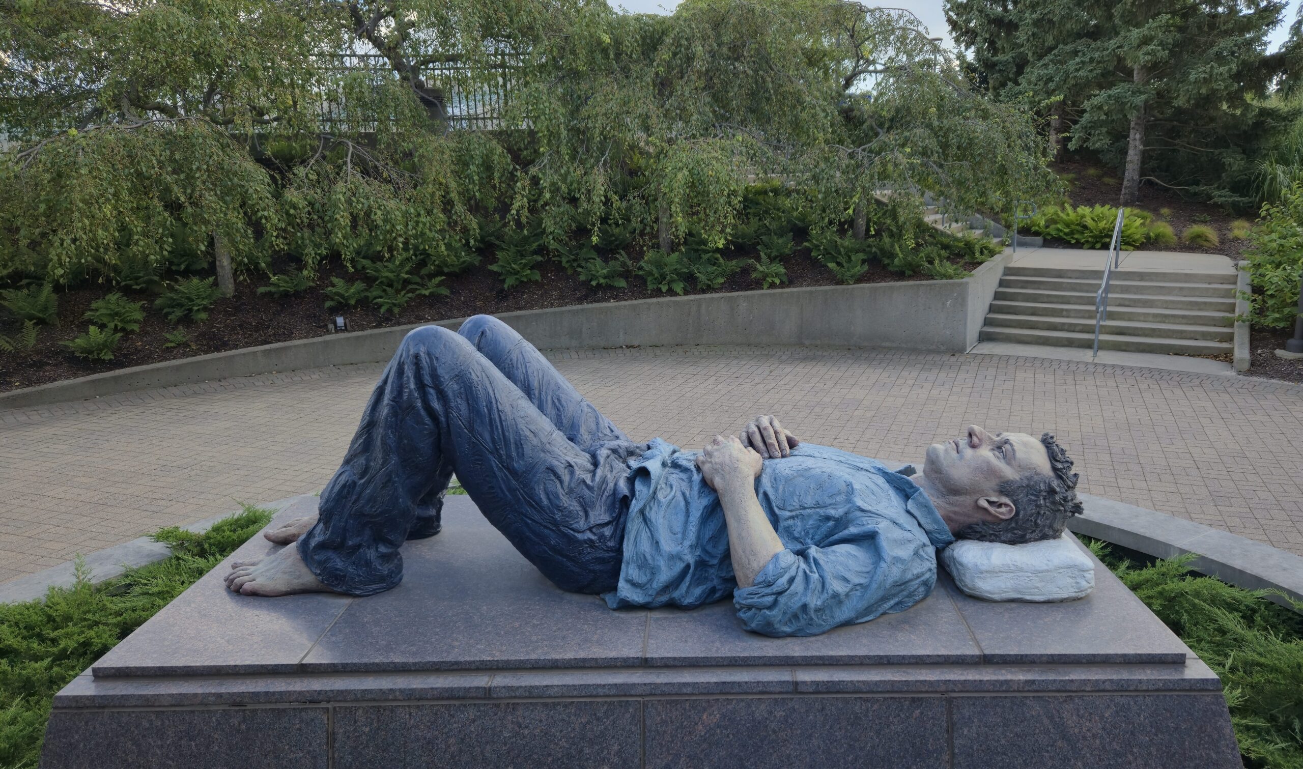 A sculpture of a man laying down, looking at the sky, in Meijer Gardens & Sculpture Park in Grand Rapids, Michigan