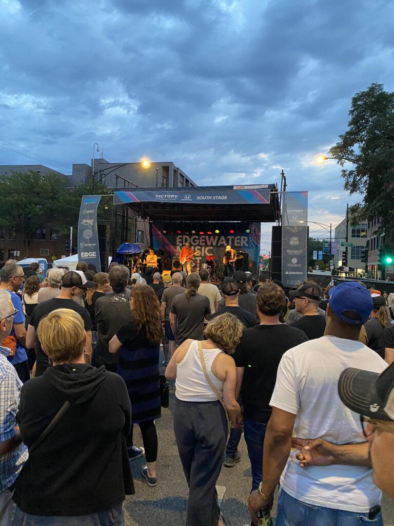 A crowd of spectators watch a band perform on a stage at a Chicago summer festival