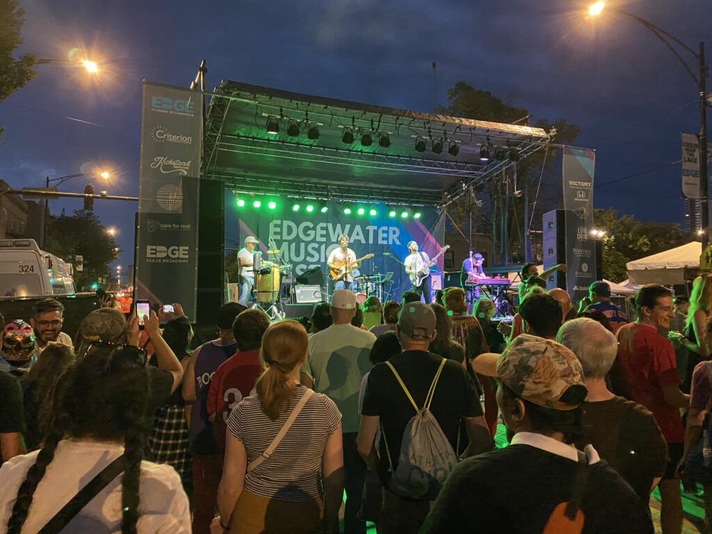 A rock band performinng on a lit stage at night in Chicago at a summer music festival