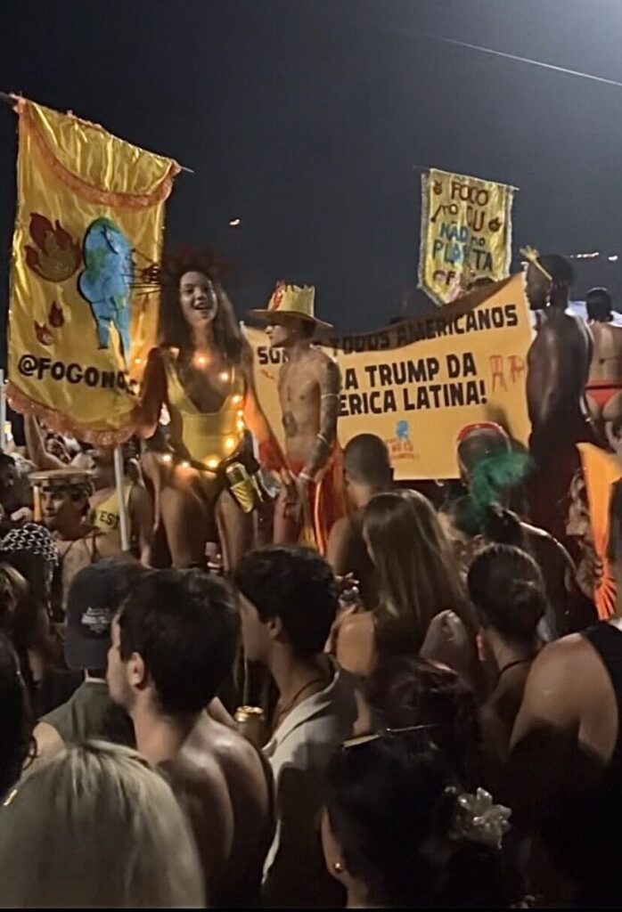 A Carnival bloco in Rio de Janeiro with performers on stilts, holding signs