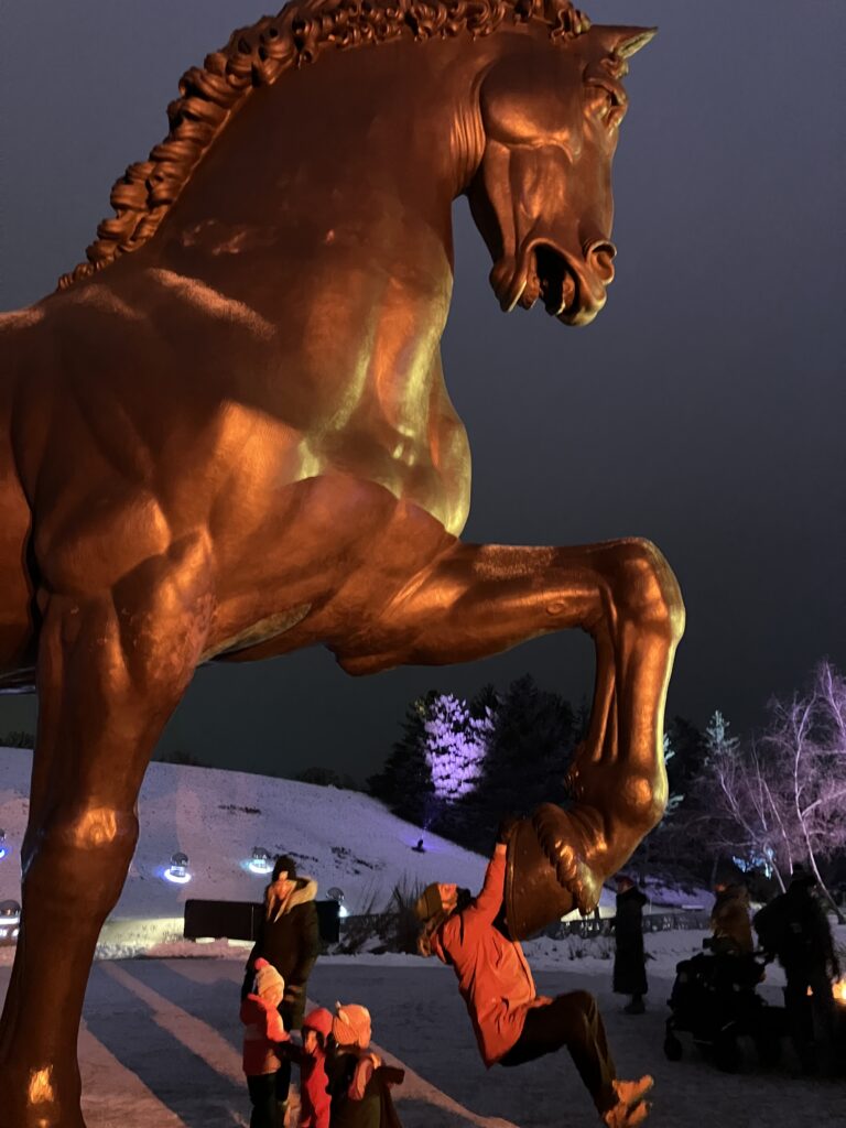 A gigantic horse sculpture in Meijer Gardens in the winter, lit by cool lights.